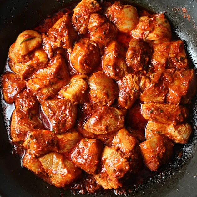 Saute pan with harissa chicken cooking on stovetop
