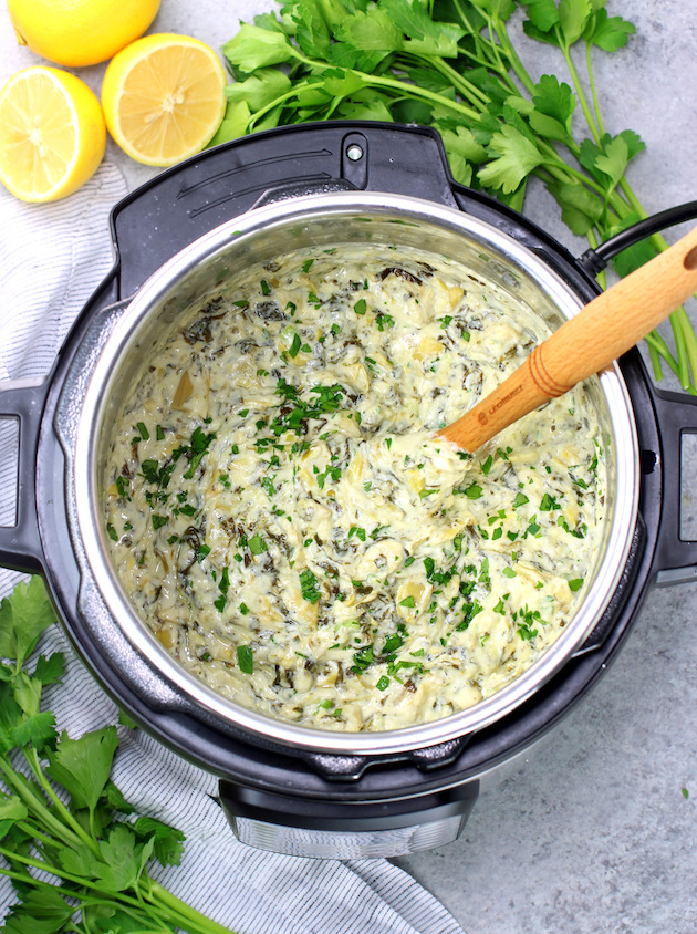 Low carb spinach artichoke dip in an instant pot with wooden spon