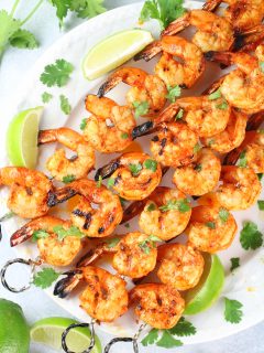 skewers of grilled gulf shrimp on platter with limes